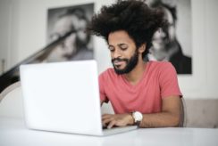 Man In Red Crew Neck T Shirt Using Laptop Vignette