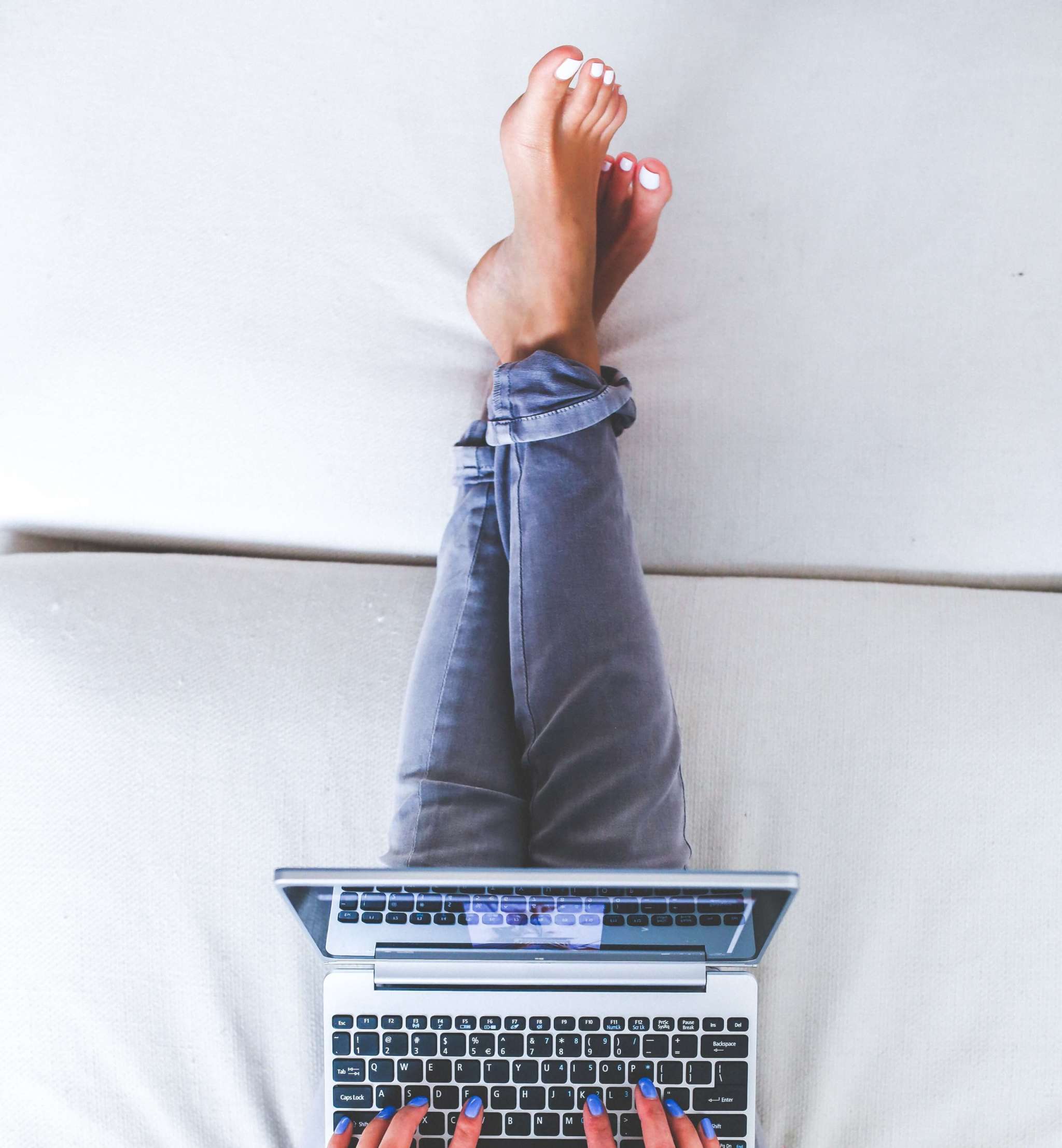 Woman Lying And Typing On Laptop