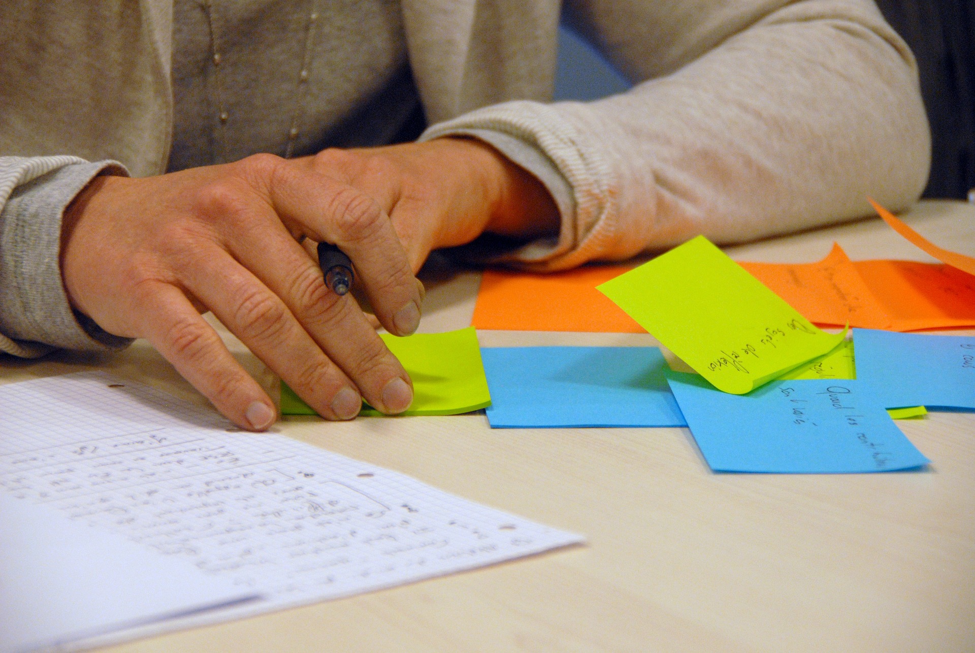 Picture of a man holding a pen and writing on post its